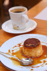  spanish flun pudding dessert closeup photo with teaspoon and cup of coffee on the background