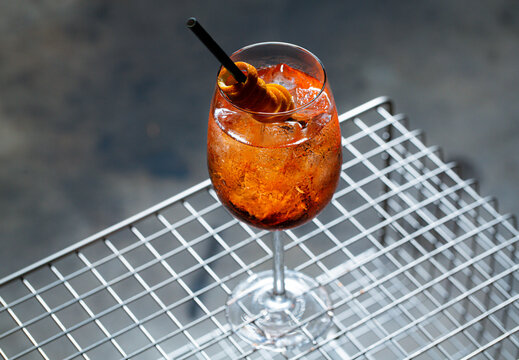 Aperol Spritz refresher sitting on antique magazine table with metal grate. Vertical shot