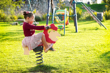 Niña feliz en un caballo de madera jugando en el parque disfrutando y viviendo alegre divertida al...