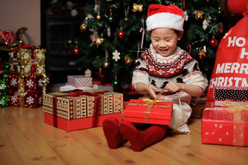 Obraz na płótnie Canvas young girl unpacking Christmas gift box beside Christmas tree at home
