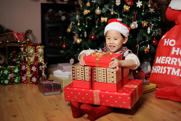 Fototapeta na wymiar young girl unpacking Christmas gift box beside Christmas tree at home