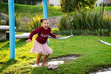Niña feliz hermosa saltando brincando jugando en un charco de agua con tierra y lodo disfrutando...