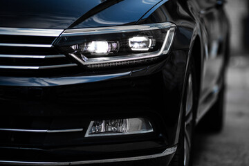 Fototapeta na wymiar Headlights of modern black car close up.
