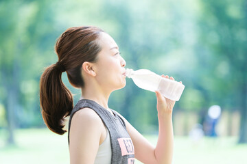 公園で運動（ヨガ）中に水分を補給する女性