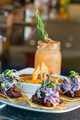 Pork Belly Tacos topped with Elote Slaw and Queso Fresco with a side of Refried Beans
