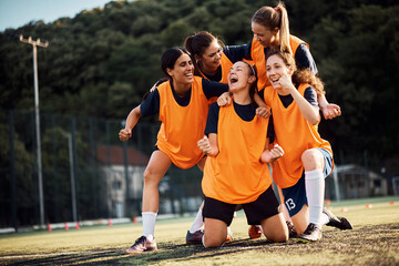 Cheerful women's soccer team celebrating victory on playing field. © Drazen
