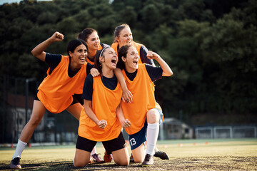 Female soccer players scream while celebrating after winning the match on stadium.