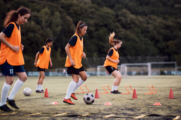 Athletic woman exercising with ball during soccer training on playing field.