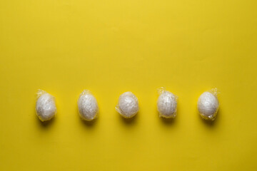 the easter eggs wrapped in traslucent plastic foil flat lay on the pastel background