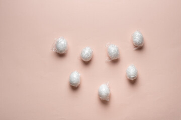 the easter eggs wrapped in traslucent plastic foil flat lay on the pastel background