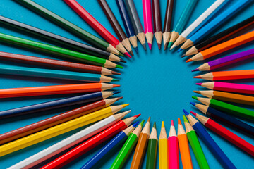 creative idea of colorful crayons making a circle shape on the pastel background