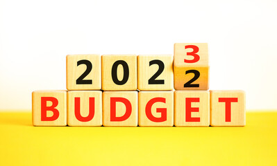 Planning 2023 budget new year symbol. Turned a wooden cube and changes words Budget 2022 to Budget 2023. Beautiful yellow table white background, copy space. Business 2023 budget new year concept.