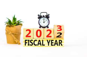 2023 fiscal year symbol. Wooden cubes with words 2022 Fiscal year to 2023 Fiscal year. Beautiful white table white background. Black alarm clock. Business and 2023 fiscal year concept. Copy space.