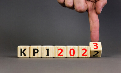 KPI, key performance indicator symbol. Businessman turns wooden cubes with words KPI 2022 and KPI 2023 on beautiful grey background, copy space. Business KPI key performance indicator concept.