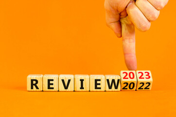 2023 review new year symbol. Businessman turns a wooden cube and changes words Review 2022 to...