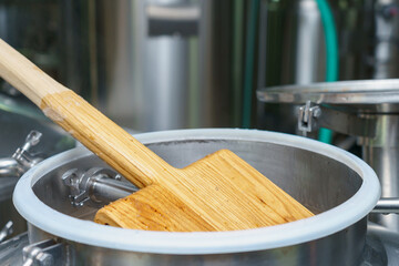 Wooden stirrer in the process of brewing beer. Background with selective focus and copy space