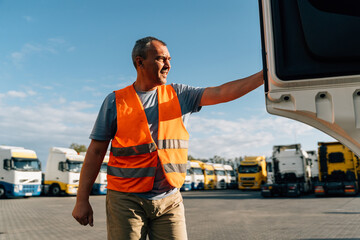 Portrait of caucasian mature man on semi-truck vehicles parking background. Truck driver worker 