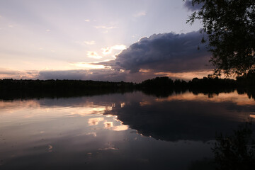 Dramatic sky over the water in rural scene. Symmetry of clouds in a lake at sunrise or sunset.