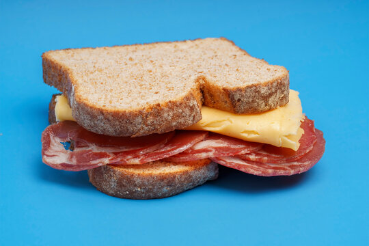 tempting bondiola and cheese sandwich in sliced whole wheat bread on blue background