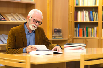 Senior man reading book in the library