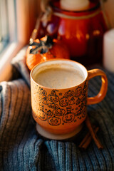 Coffee cup with pumpkins, cinnamon sticks, Thanksgiving or Halloween decorations on knitted plaid. Autumn mood, hygge cozy home interior decor.