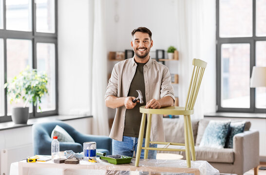 Furniture Restoration, Diy And Home Improvement Concept - Happy Smiling Man With Hammer And Nail Repairing Old Wooden Chair