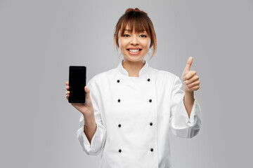 cooking, culinary and people concept - happy smiling female chef in white jacket with smartphone...