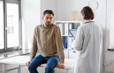 Obraz premium medicine, healthcare and people concept - female doctor with clipboard and male patient having health problem at hospital