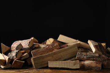 Cut firewood on table against black background