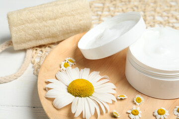 Obraz na płótnie Canvas Jar of cream and chamomiles on wooden plate, closeup