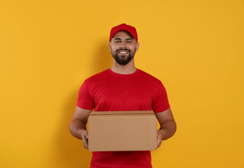 Courier holding cardboard box on yellow background