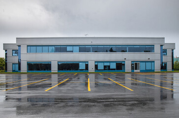 Obraz premium Exterior of a rundown warehouse building two storey stucco, multilane windows, curtains, dusk, shadows, garbage in foreground, nobody