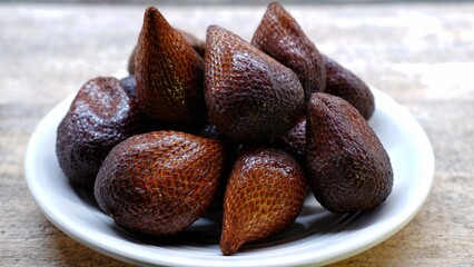 A plate of snake fruits on wooden background 