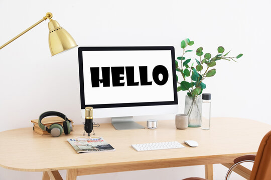 Modern computer with word HELLO on screen in room