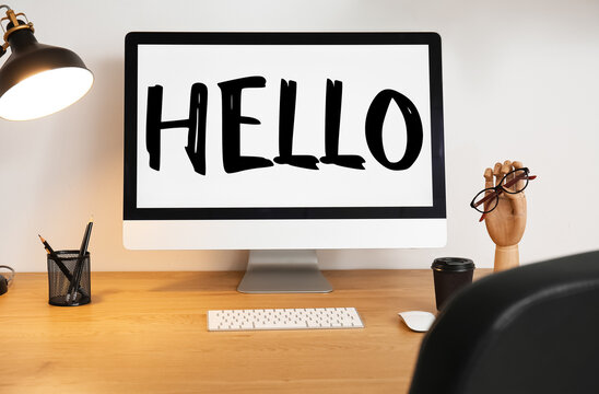 Modern computer with word HELLO on screen at workplace