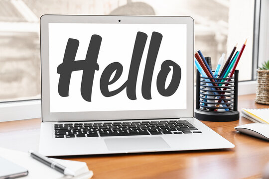 Modern laptop with word HELLO on screen in office