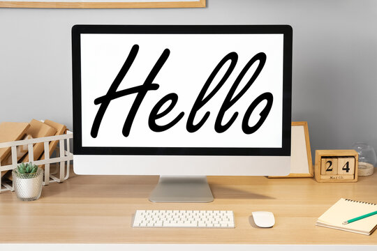 Modern computer with word HELLO on screen in room - Powered by Adobe