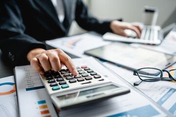 Businesswomen or Accountants use a calculator to work with financial statements and analyze company...