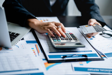 Businesswomen or Accountants use a calculator to doing income-expense accounting and analyze company financial reports. investment, balance sheets, taxes, planning and business strategies concept.