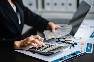 Fototapeta premium Businesswomen or Accountants use a calculator to doing income-expense accounting and analyze company financial reports. investment, balance sheets, taxes, planning and business strategies concept.