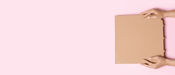 Hands with cardboard pizza box on pink background with space for text, top view