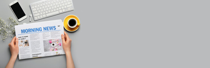 Female hands with newspaper, PC keyboard, phone and cup of hot coffee on grey background with space for text