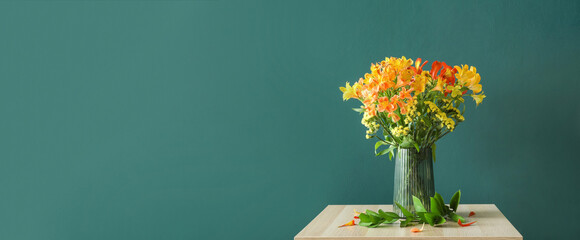 Vase with bouquet of beautiful alstroemeria flowers on table against green background with space...