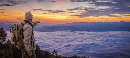 Hipster male hiker with backpack enjoying sunset on peak of foggy mountain. Tourist traveler on background view mockup.  Panoramic