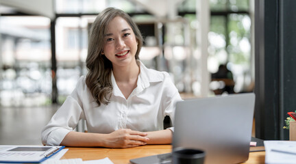 Image of young beautiful joyful woman smiling while working with laptop in office