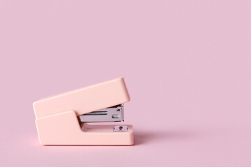Pink stapler on color background