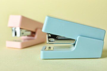 Office staplers on color background, closeup