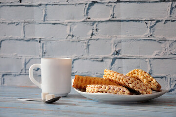 Assorted fresh cream waffles and a cup of hot coffee with sugar on a wooden table.