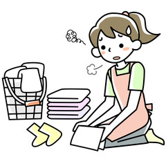 疲れた表情で洗濯物をたたむ若い女性