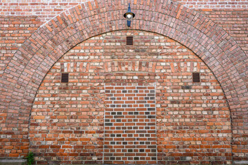 Brick wall with arches and bricked up doorway, as a patterned background
